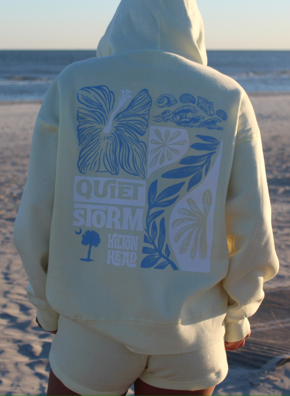 Person wearing a hoodie with a design on the beach