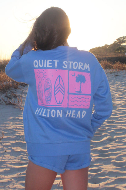 Person wearing a blue sweatshirt with 'Quiet Storm Hilton Head' on a beach